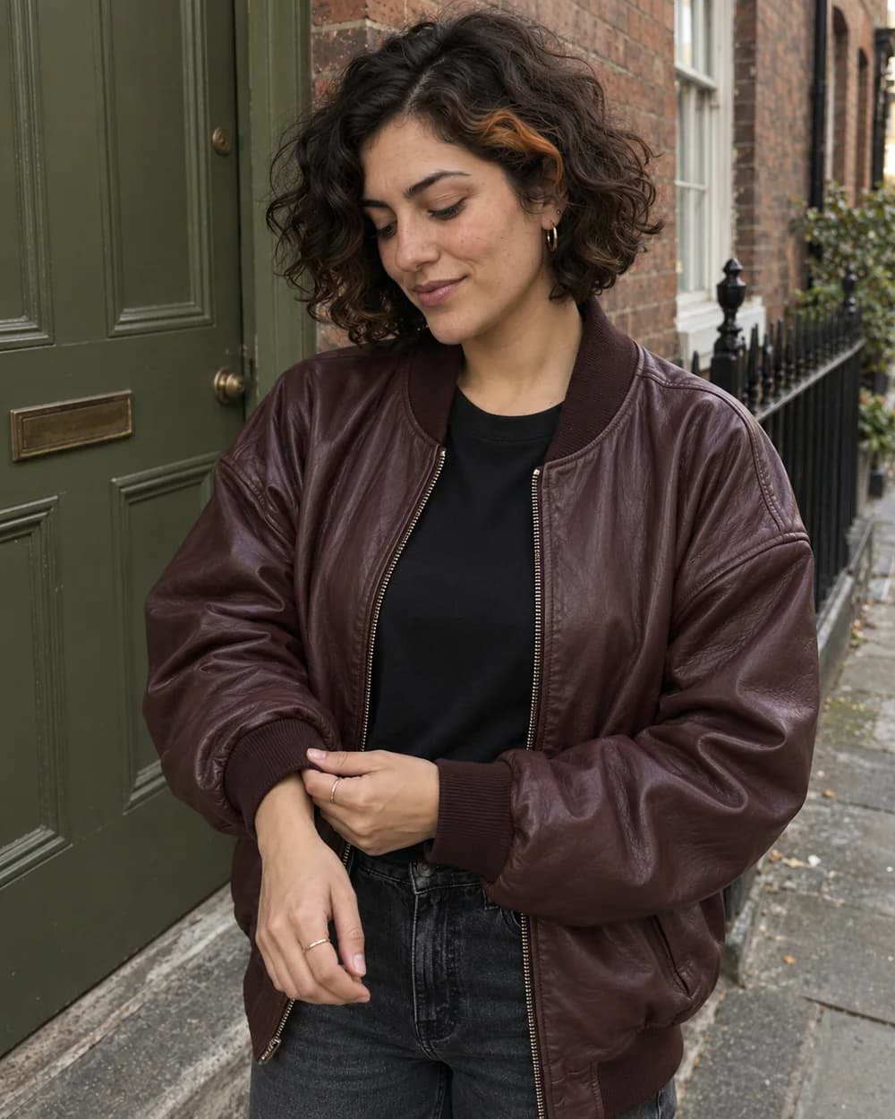 Closer view of the same creator adjusting a burgundy bomber cuff