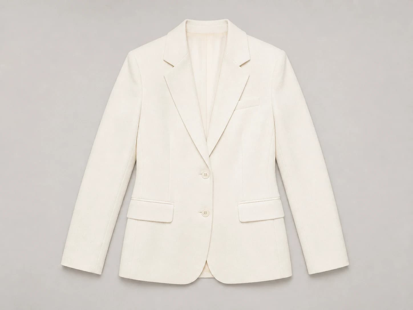 Illustrative ivory blazer reference with two front buttons and flap pockets