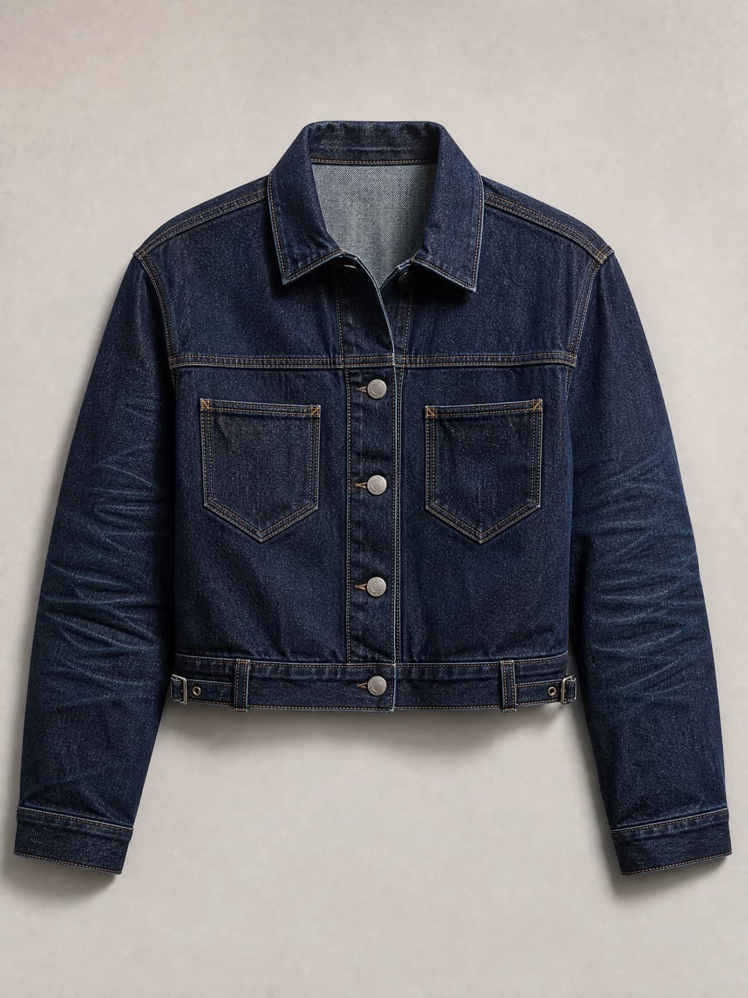 Fictional cropped indigo denim jacket with tobacco stitching and metal hardware.
