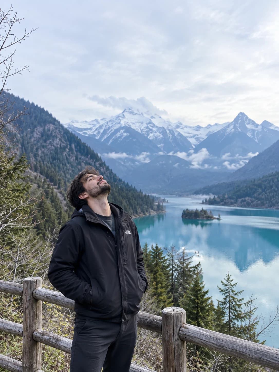 Adult male virtual creator beside a wooden fence above a turquoise alpine lake