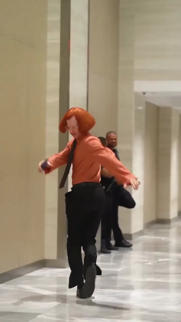 Don Nuger source video at eleven seconds, turning while moving past the people in the hallway
