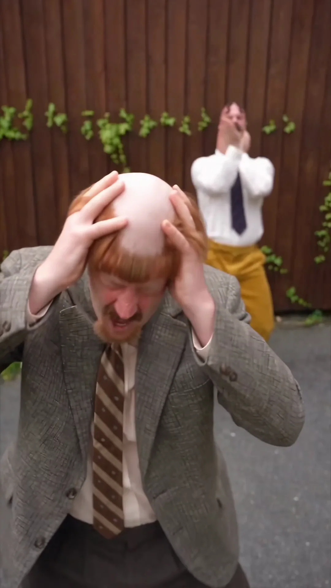 Source video at 7.5 seconds: Harold is now nearest the camera holding his head while Madman reacts behind him in the same yard