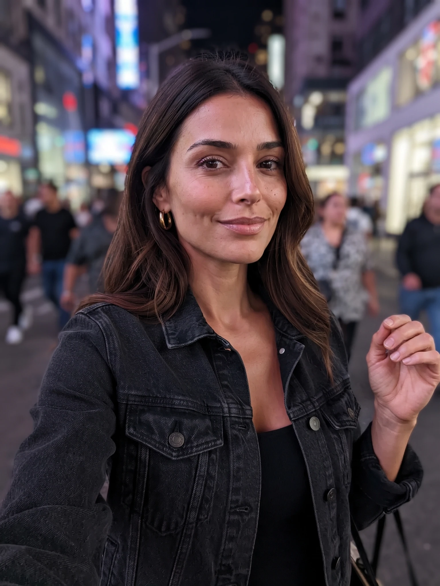 A fictional adult AI influencer taking a night street selfie with soft city glow.