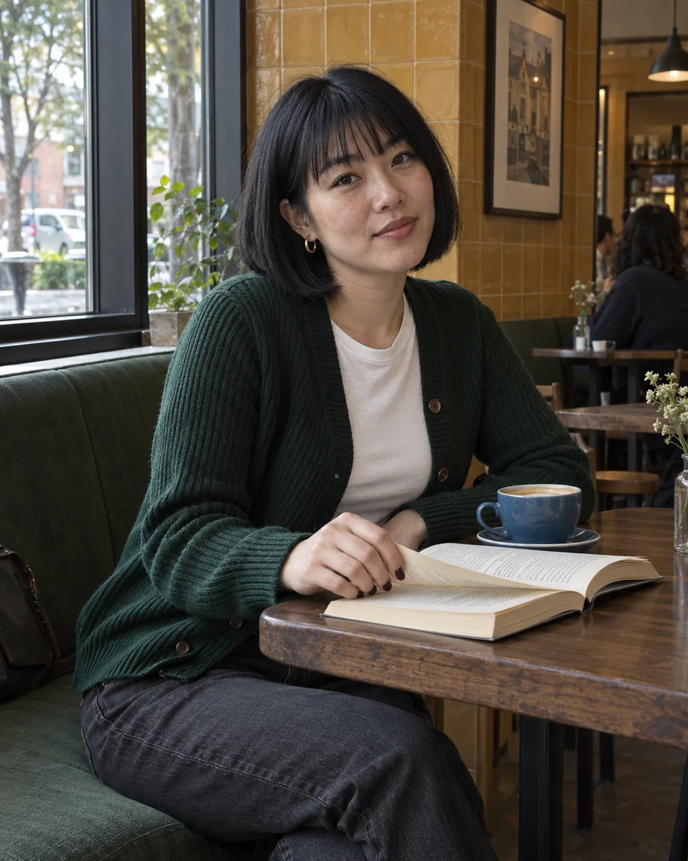 Seated at a café table with an open book; consistent café creator example