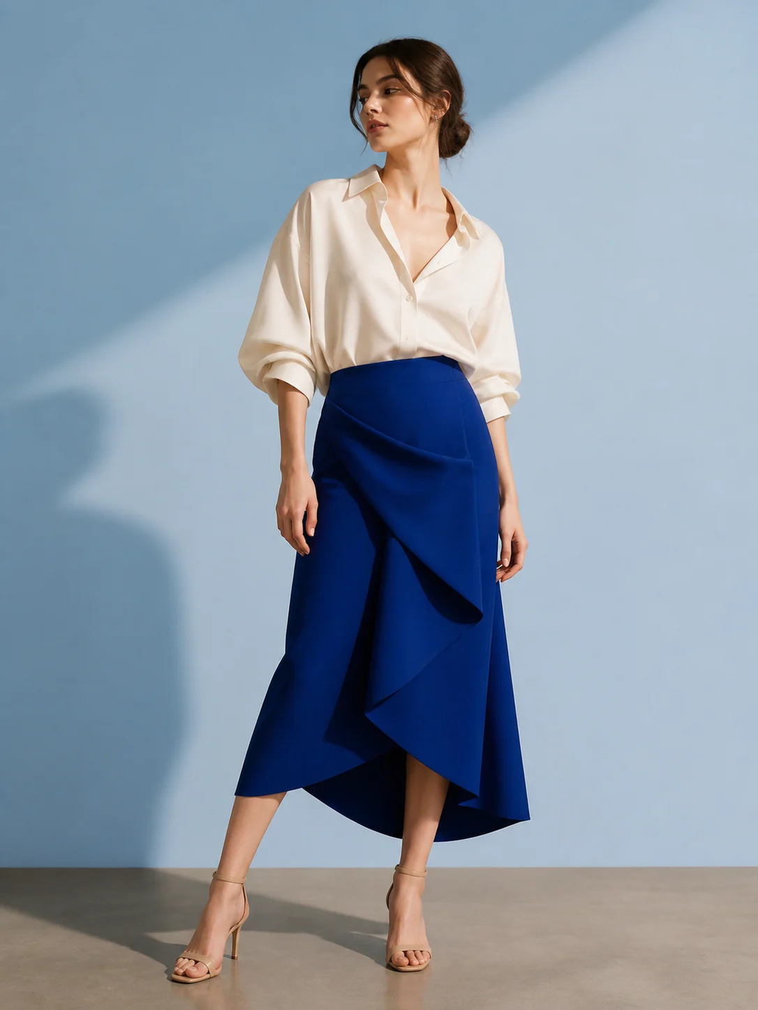 AI-generated illustrative fashion campaign of a fictional adult in an ivory shirt and cobalt skirt in a blue studio